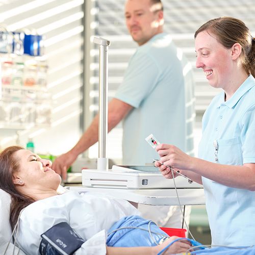 Pflegefachpersonen kümmern sich um eine Patientin